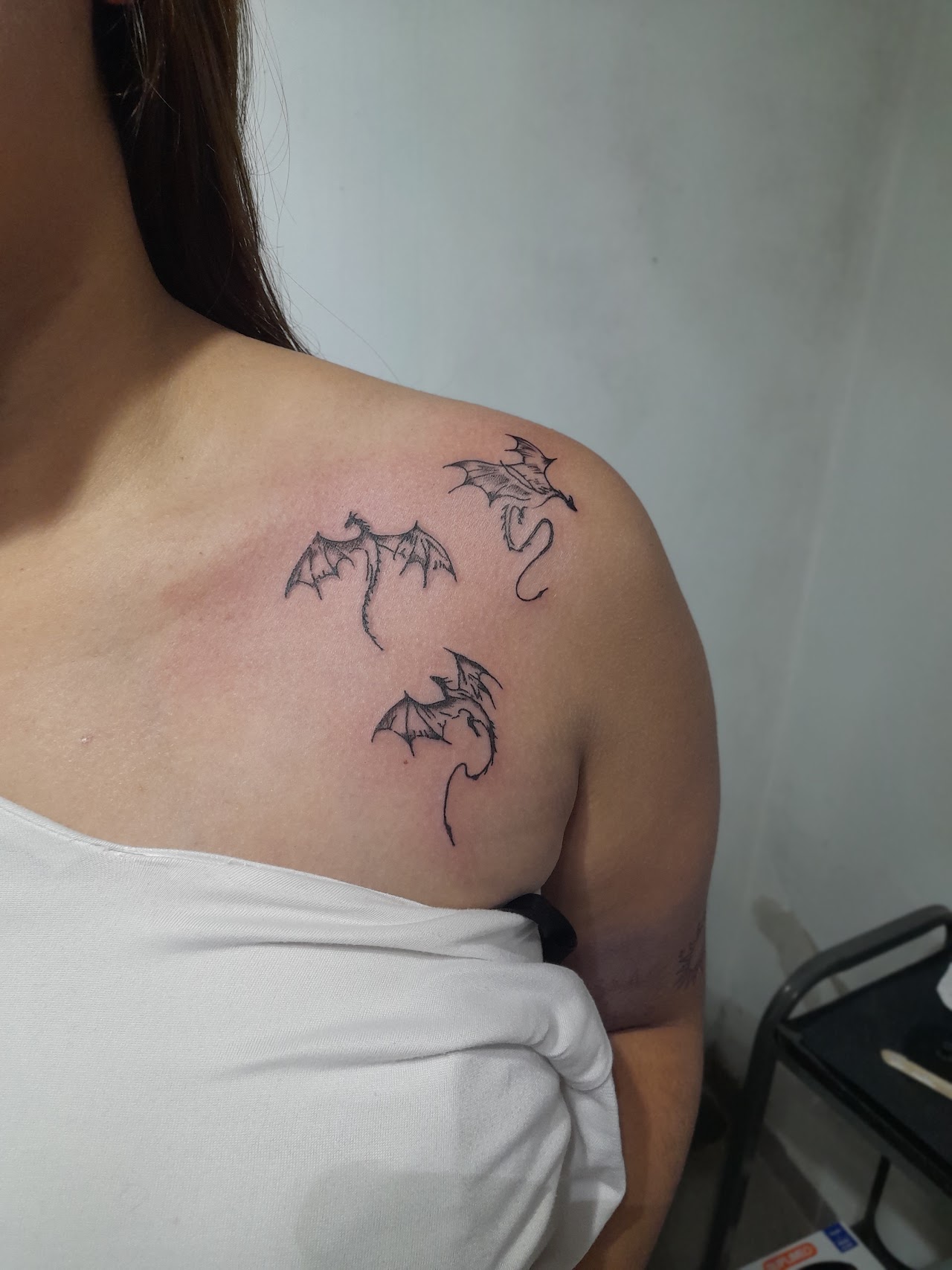 Tatuaje gótico de cuervo sobre calavera con rosas y arco ojival en hombro